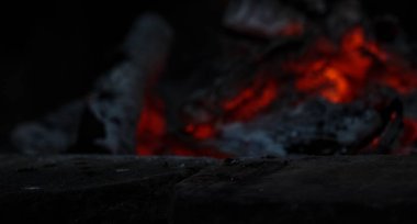 Arkaplanda şömine alevi olan koyu renkli bir taş ürün ön planı