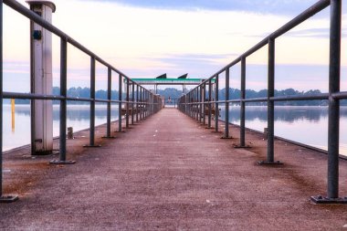 Gökyüzü ve gölün arka planında metal tırabzanlar olan boş iskele.