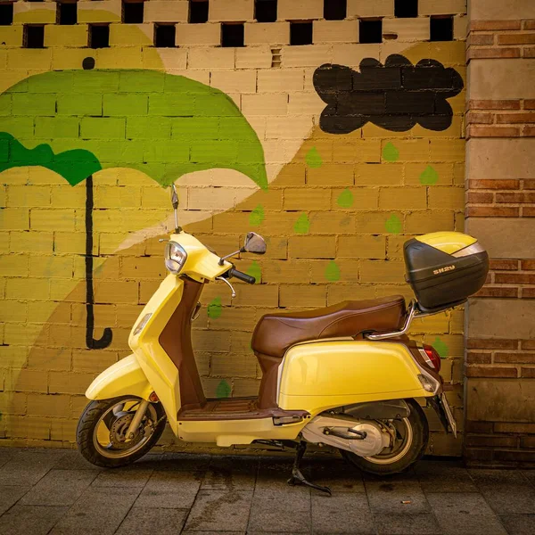 明亮的黄色摩托车靠在五颜六色的砖墙上 — 图库照片