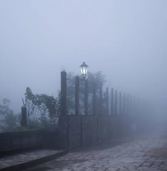 霧に覆われた街灯のある通りに美しくモダンなフェンス — ストック写真