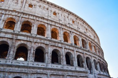 Açık mavi gökyüzü arkaplanındaki belirgin Colosseum amfi tiyatrosunun yakın plan çekimi.