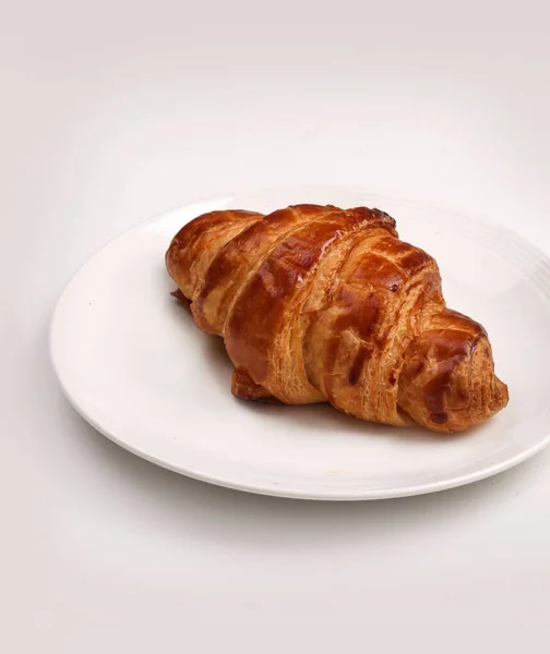 Tiro Vertical Croissant Amanteigado Francês Uma Placa Fundo Branco — Fotografia de Stock