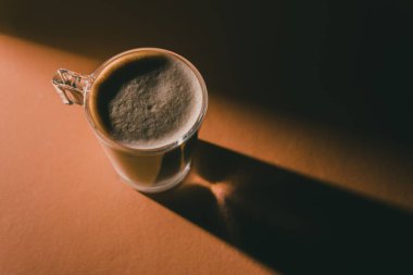 Kırmızı bir masanın üstünde köpüklü kahve bardağının üst görüntüsü.