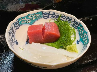 Deniz yosunu ve shiso ya da Çin fesleğeni ve suşi barında ince dilimlenmiş Japon wasabi at turpu üzerine kalın bir çiğ ton balığı.