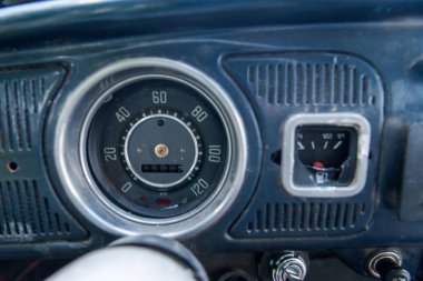 Gösterge paneli ve kilometre sayacı olan eski bir VW böceğinin iç kısmı.