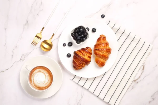 Horní Pohled Croissanty Borůvkami Cappuccino Podávané Bílém Stole — Stock fotografie