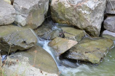 Nehirdeki büyük gri taşların üzerindeki güzel bir su akıntısına yakın çekim.