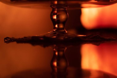 Kahverengi ışıkların altında yansıtıcı bir yüzey üzerinde cam bir vazoya yakın çekim