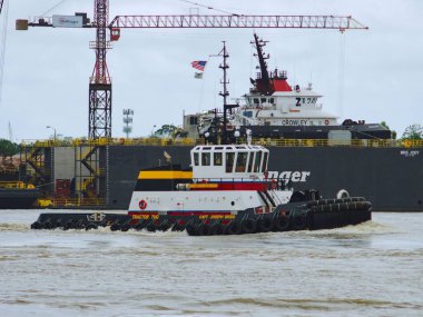 New Orleans 'ta Mississippi Nehri' nde arka planda bir vinçle ilerleyen römorkör.