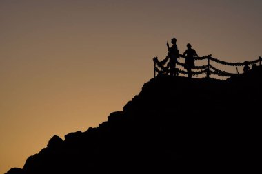 Gün batımında Kanarya Adaları 'ndaki bir tepenin tepesindeki insan siluetlerinin alçak açısı.