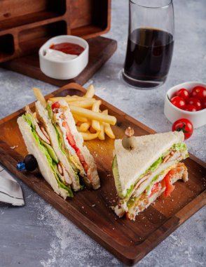 Tahtada patates kızartması olan üçgen kulüp sandviçleri.