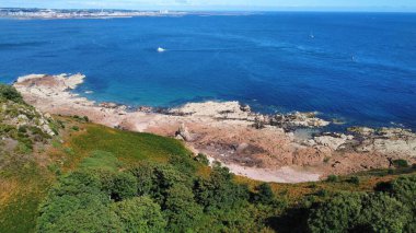 Sakin, güneşli sahil üzerindeki yeşil yüksek geçitlerin güzel manzarası.