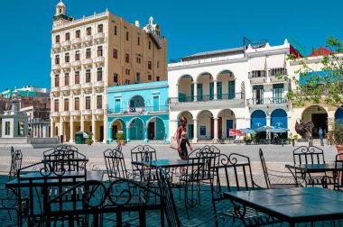 Gündüz vakti bir Karayip şehrinin ana meydanının dış görünüşü. Masalarda yürüyen bir insan ve mavi gökyüzü olan eski bir mimari..