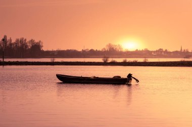 Nehirdeki tekne güzel günbatımının arka planında.