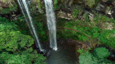 Bitki ve kayalarla çevrili bir şelalenin havadan çekilmiş görüntüsü.