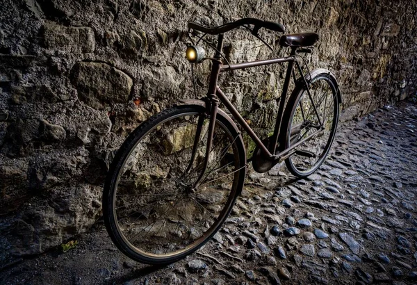一辆老式锈迹斑斑的自行车停在铺了路的石墙边 — 图库照片