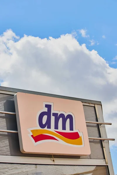 A billboard of dm logo against a background of sky and clouds