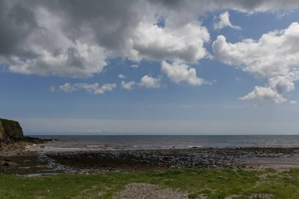 Malowniczy Widok Plażę Pokrytą Zieloną Trawą Przeciwko Falom Oceanicznym Irlandii — Zdjęcie stockowe