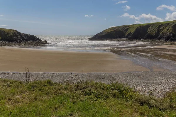 Malowniczy Widok Plażę Pokrytą Zieloną Trawą Przeciwko Falom Oceanicznym Irlandii — Zdjęcie stockowe