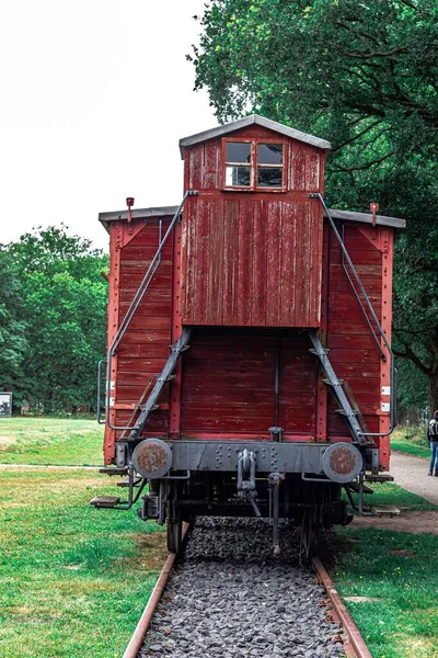 美しい緑の風景を通って道路上の木製の赤い馬車と列車の後ろ — ストック写真