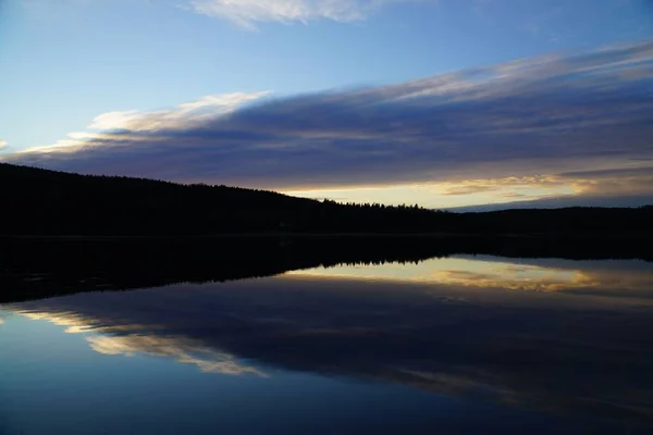 Uma Vista Panorâmica Silhuetas Colinas Nuvens Refletindo Lago Pôr Sol — Fotografia de Stock