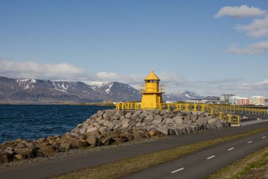 Reykjavik 'in kayalık sahilindeki tarihi sarı Hofoi deniz feneri.