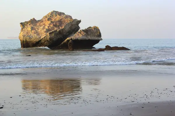 大石头白天在水里冲刷沙质海岸的一块大石头 — 图库照片