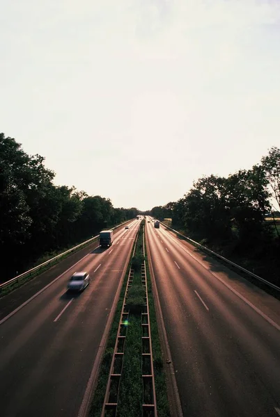 Вертикальный Снимок Двухполосной Автострады Автомобилями Окруженными Деревьями Обе Стороны — стоковое фото