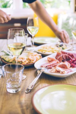 Bir bardak beyaz şarapla servis edilen antipasto tabağı.