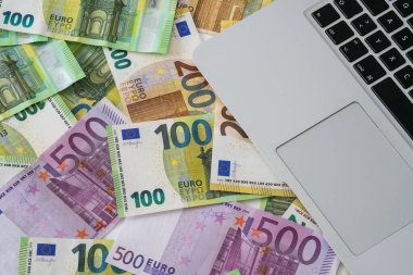 Avro banknotları yığını ve masadaki bir dizüstü bilgisayar - iş ve yatırım kavramı