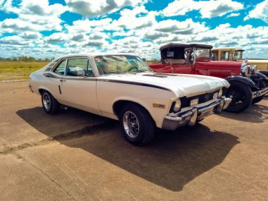 Eski beyaz spor Chevrolet Chevrolet 250 SS Super Serie 2 coupe 1970 'ler GM tarafından bir uçak pistine park edilmiş. Arka planda 2. Dünya Savaşı bombacısı. CADEAA MNA 2022