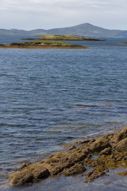 Güzel manzaralı, sakin bir deniz suyu ve uzak İrlanda, İngiltere 'deki küçük adaların dikey görüntüsü.
