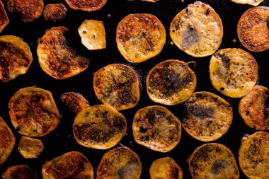 Yağlı tavada kızaran patates dilimlerinin üst görüntüsü.