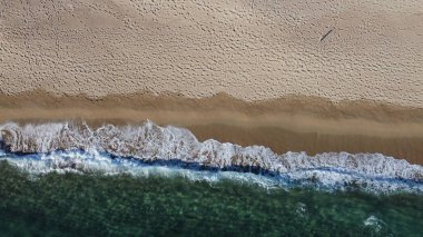 Okyanus dalgalarının ve kumlu sahillerin havadan çekilmiş görüntüsü.