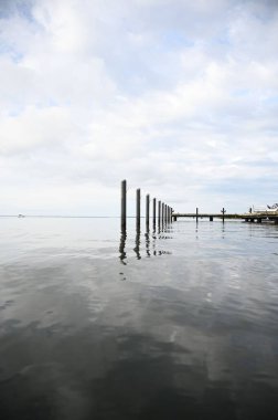 Dikey bir tahta dalga kırıcı görüntüsü ve okyanusta mavi bulutlu bir rıhtım.