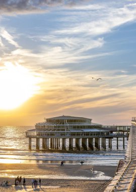 Gün batımında Scheveningen de Pier 'de yürüyen insanların dikey görüntüsü.