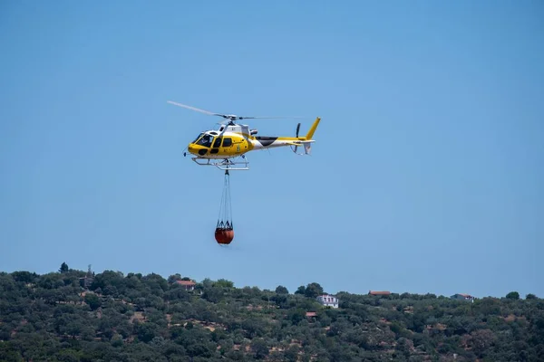 화염에 다니는 바구니를 운반하는 소방용 헬리콥터 뒤에는 하늘로 놓는다 — 스톡 사진