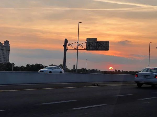 黄色の空に沈む夕日の美しいショットと前景に車のある道路 — ストック写真