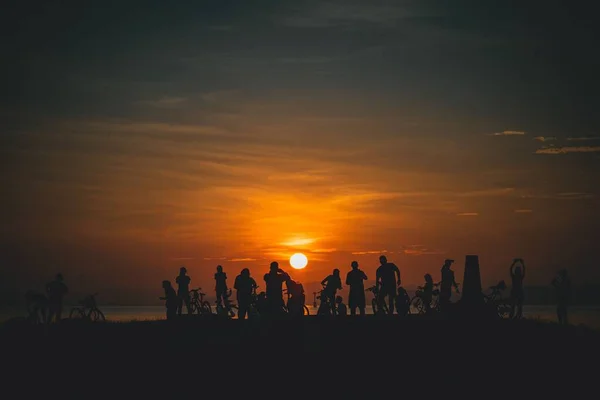 Силуэты Группы Велосипедистов Стоящих Перед Океаном Против Солнца Закате — стоковое фото