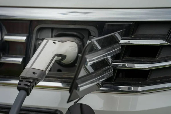 プラグ充電コードで現代の電気自動車を充電するためのクローズアップショット — ストック写真