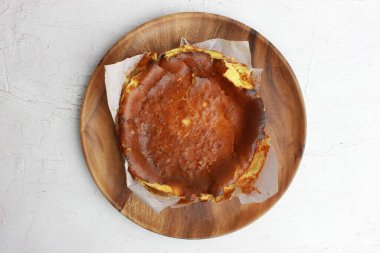 Beyaz arka planda izole edilmiş ahşap bir tabakta nefis bir cheesecake manzarası.