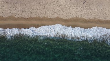 Okyanus dalgalarının ve kumlu sahillerin havadan çekilmiş görüntüsü.