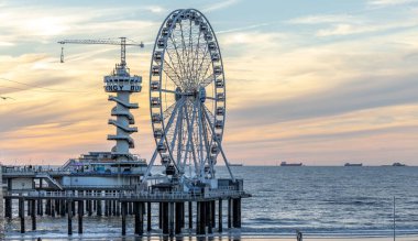 Dönme dolabın ve Piertoren 'in Scheveningse rıhtımındaki güzel günbatımı bulutlarının manzaralı bir çekimi.