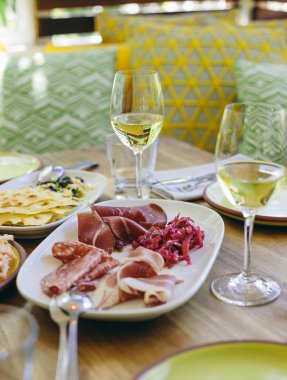 Bir bardak beyaz şarapla servis edilen antipasto tabağı.