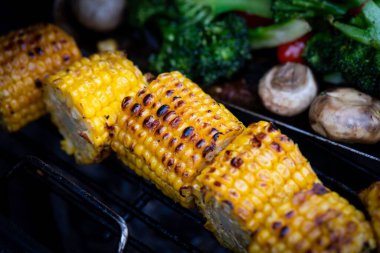 Sebzelerin yanında kavrulmuş mısırın yakın çekimi.