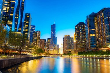 Akşamları nehrin kıyısındaki aydınlık binalar. Chicago, Amerika Birleşik Devletleri.