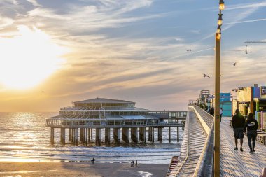 Gün batımında Scheveningen de Pier 'de yürüyen insanların güzel bir manzarası.