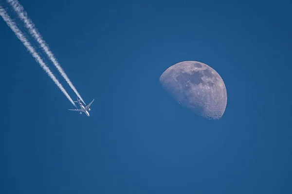 澄んだ青い空に飛行機と白い半月の息をのむような景色 — ストック写真