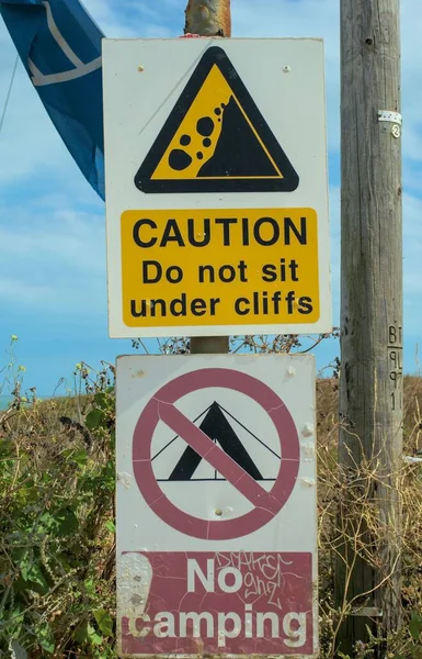 一个包含2个警告标志的垂直镜头 不要坐在悬崖下 不要露营 — 图库照片