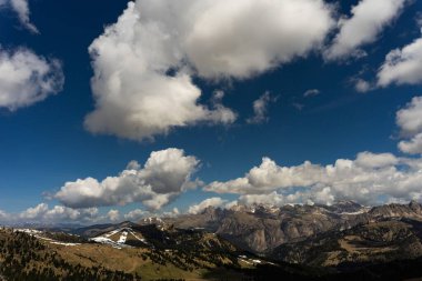 Dolomite Dağları 'nın panoramik bir görüntüsü. Güneş ışınları ve gölgelerle birlikte gün ışığında yoğun bulutlar üzerlerinde.